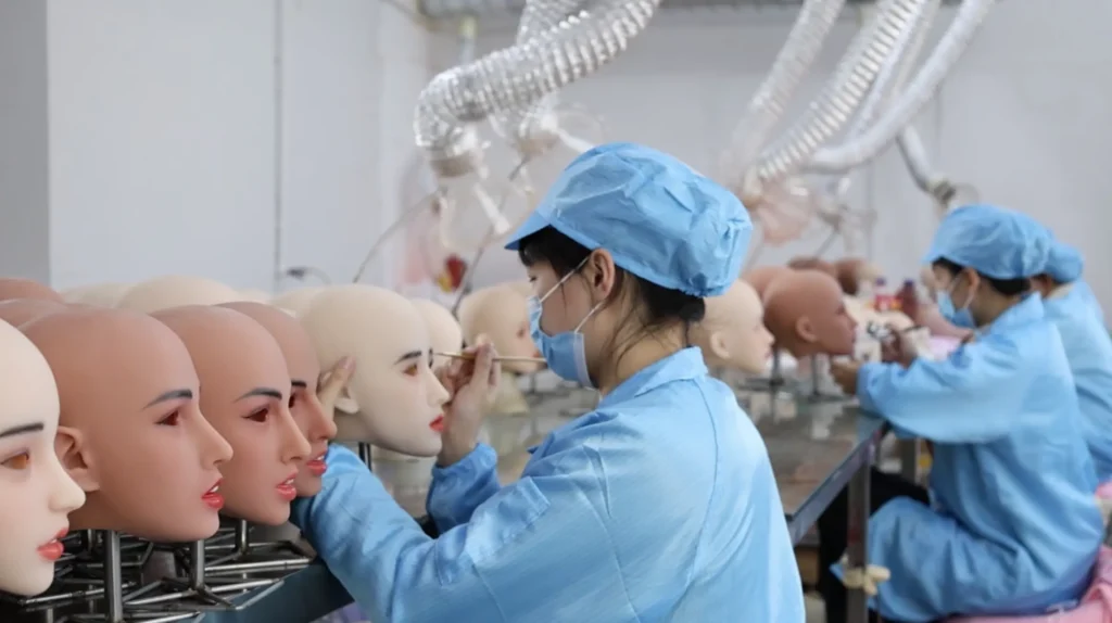The factory technicians are applying eyeliner to the silicone sex dolls.